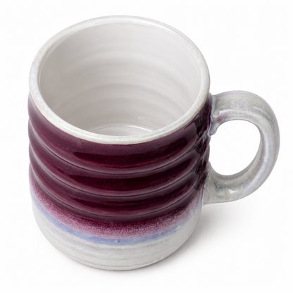 A ceramic mug with a ribbed exterior featuring a deep burgundy top section and a light gray lower section with a subtle blue-purple glaze, set against a plain white background.