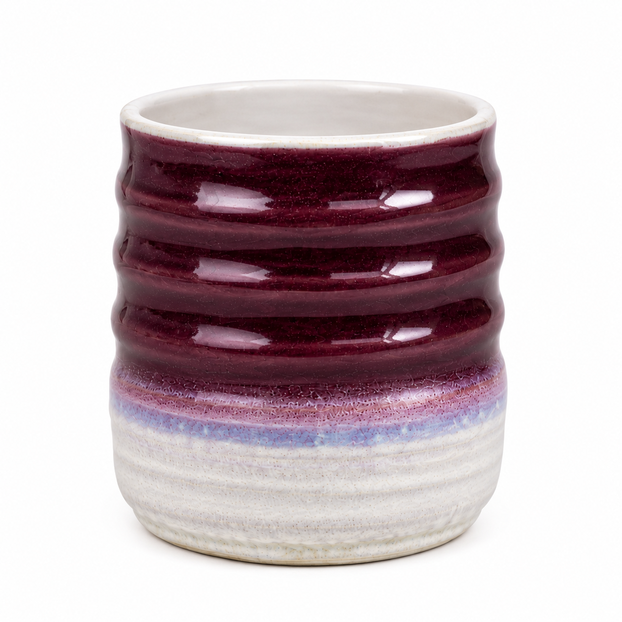 A handmade ceramic cup with a ribbed texture, featuring a deep burgundy glazed upper half and a textured off-white lower half with a subtle purple band.
