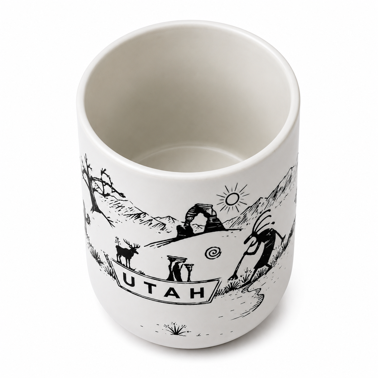 A white ceramic mug featuring a black line art illustration of Utah landmarks, including Arches National Park, a deer, a Native American figure, and the word 'UTAH' on a banner, shown on a white background.