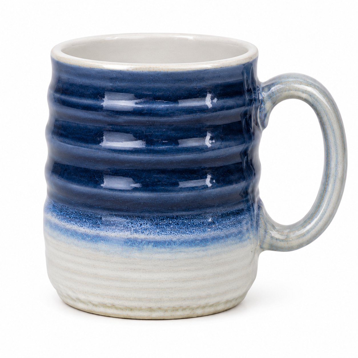 A ceramic mug with a wavy ribbed design, featuring a glossy dark blue glaze on the upper half and a textured off-white glaze on the lower half, with a matching light gray-blue handle.