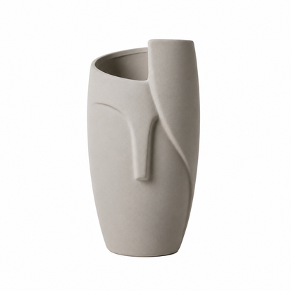 A minimalist ceramic vase in a light warm gray or greige color, featuring an abstract organic sculptural design with a curved handle and a wide, open top, set against a plain white background.