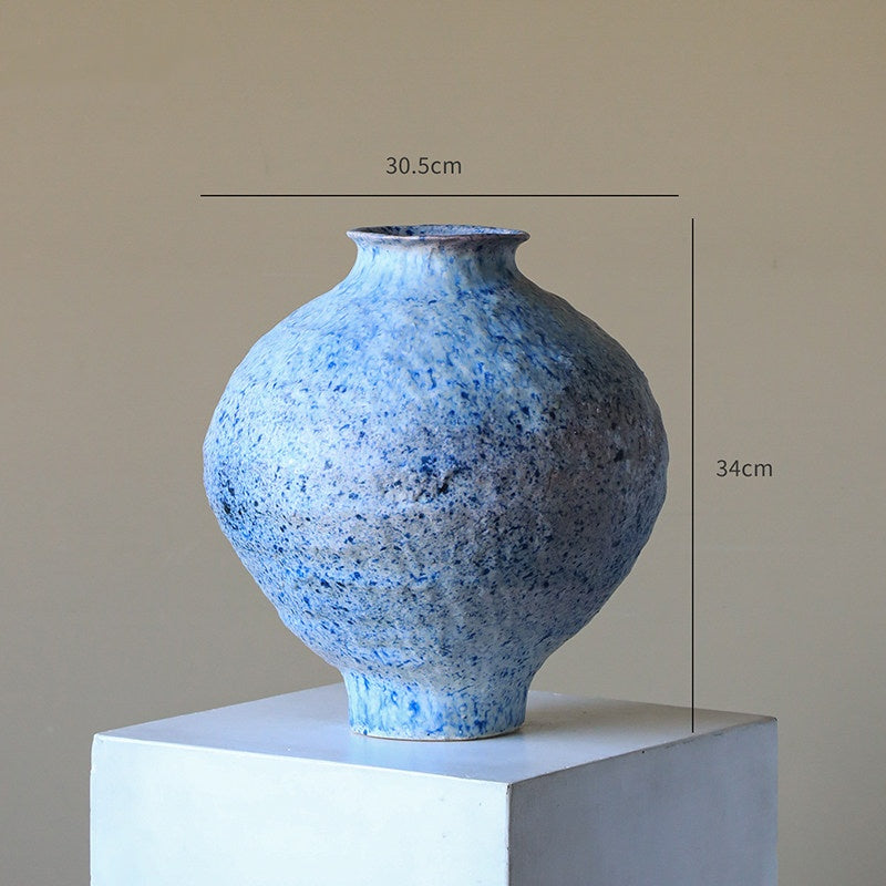 Blue speckled vase on a white pedestal with dimensions indicated