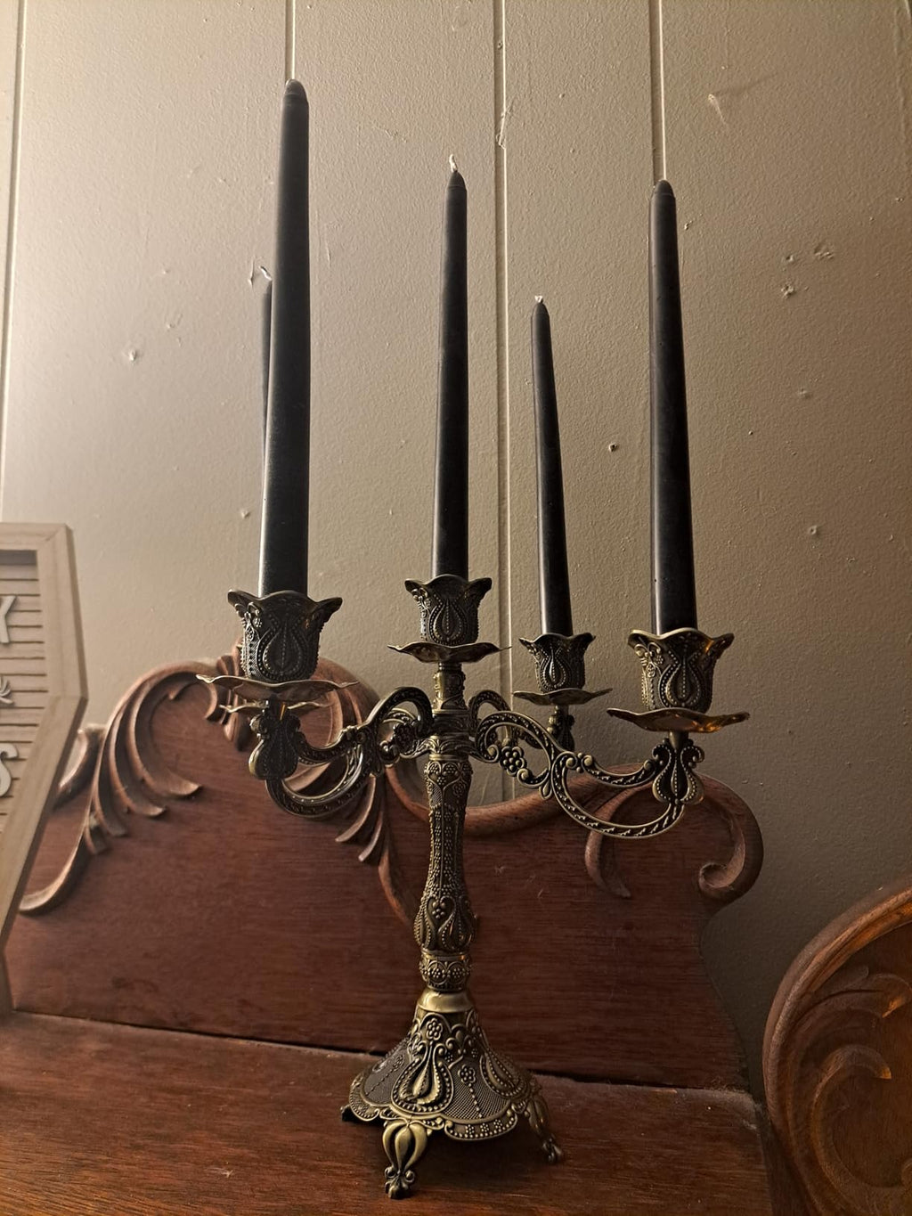 Decorative candelabrum with four black candles on a wooden surface.